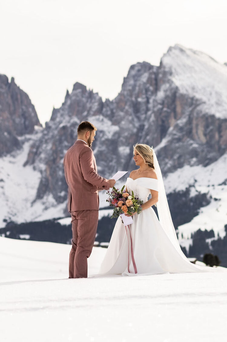 Getting legally married in Italy. A couple standing on a mountain meadow doing vows in winter.