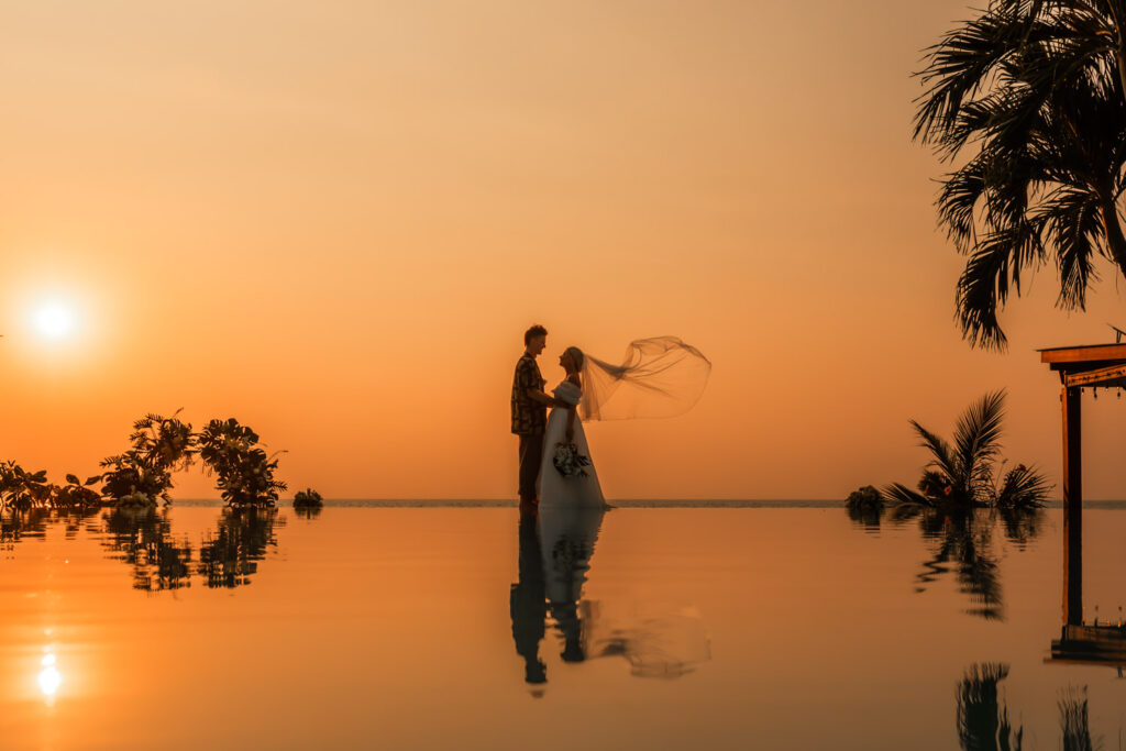 How to elope in Thailand. A couple at the end of infinity pool at sunset in Thailand.