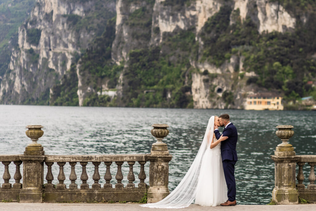 Couple standing at lake Garda in their wedding gown and kissing
