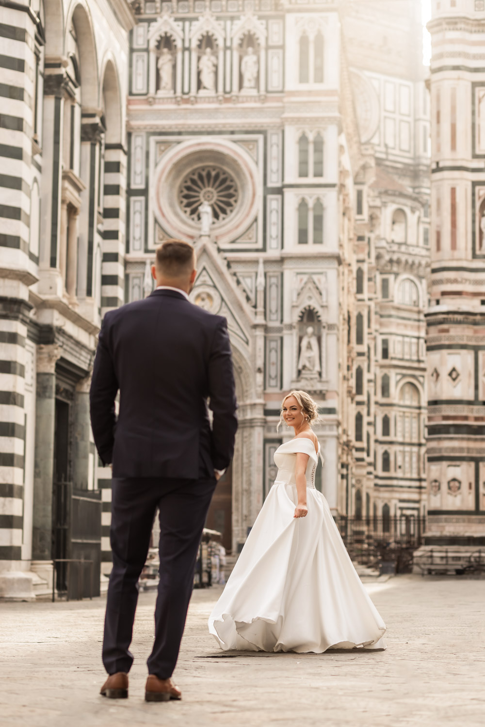 A photo of husband looking at his wife in her wedding dress in front of the dome of Florence
