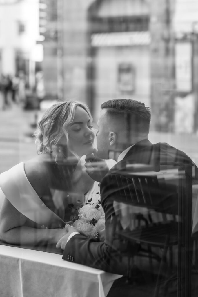 A photo taken through a window of a couple about to kiss on the street of Tuscany