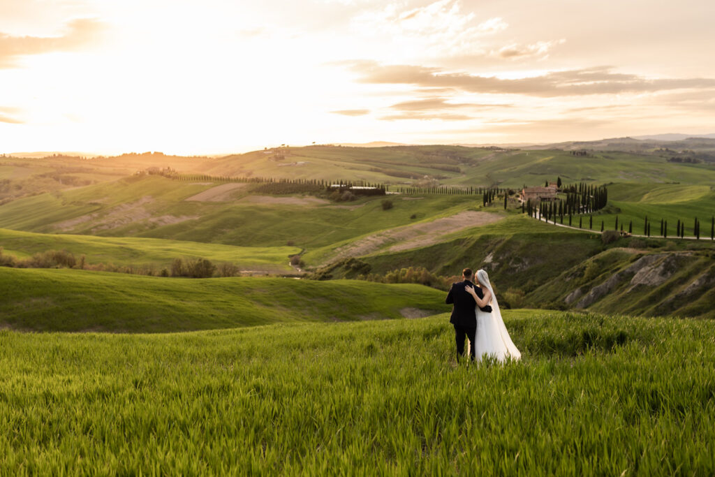 Couple standing on Tuscany hills doing their first dance at sunset.