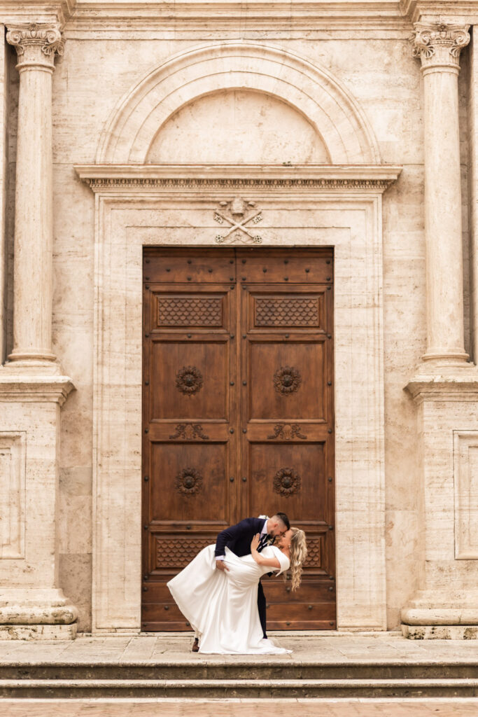Husband and wife dancing in their wedding gown in front of a big door in Italy