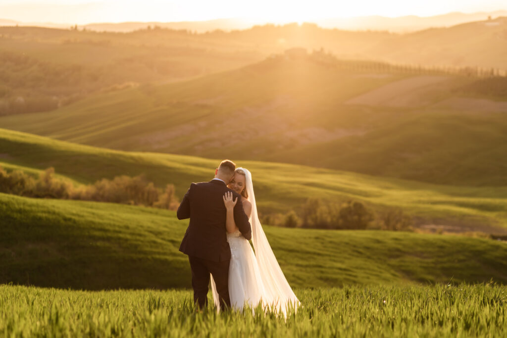 Couple standing on Tuscany hills reading their vows to each other at sunset.