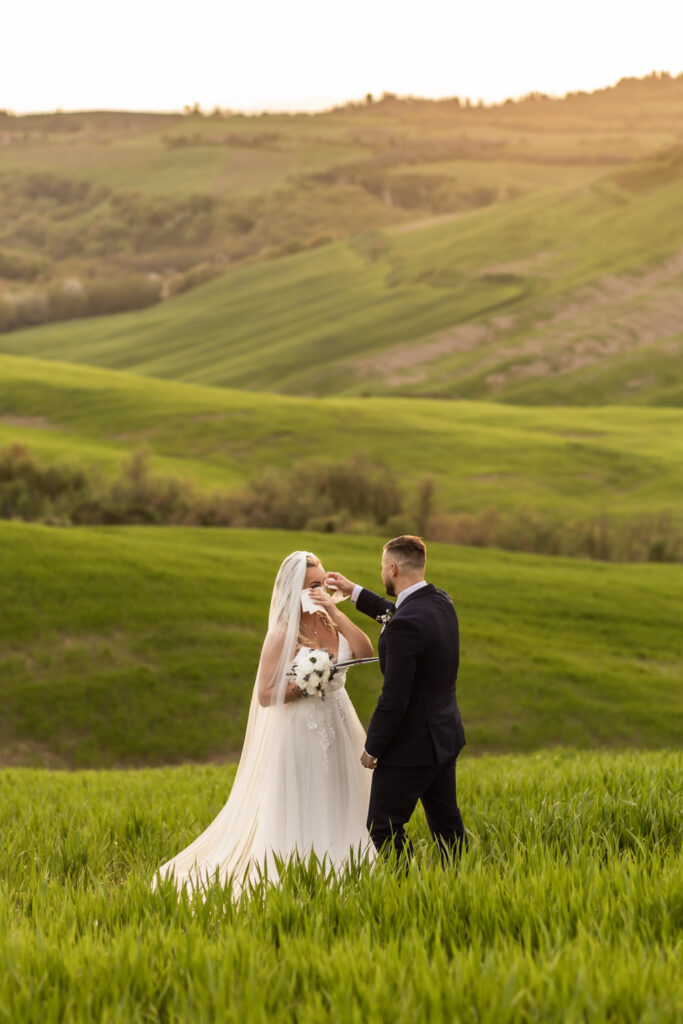Couple standing on Tuscany hills reading their vows to each other at sunset.