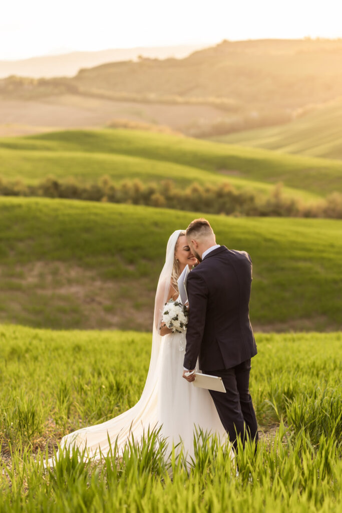 Couple standing on Tuscany hills reading their vows to each other at sunset.