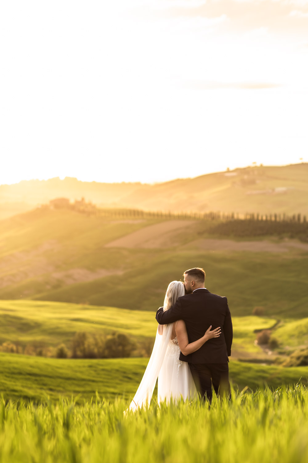 Couple standing on Tuscany hills reading their vows to each other at sunset.