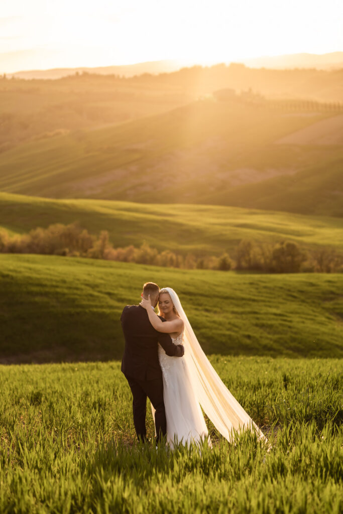 Couple standing on Tuscany hills reading their vows to each other at sunset.