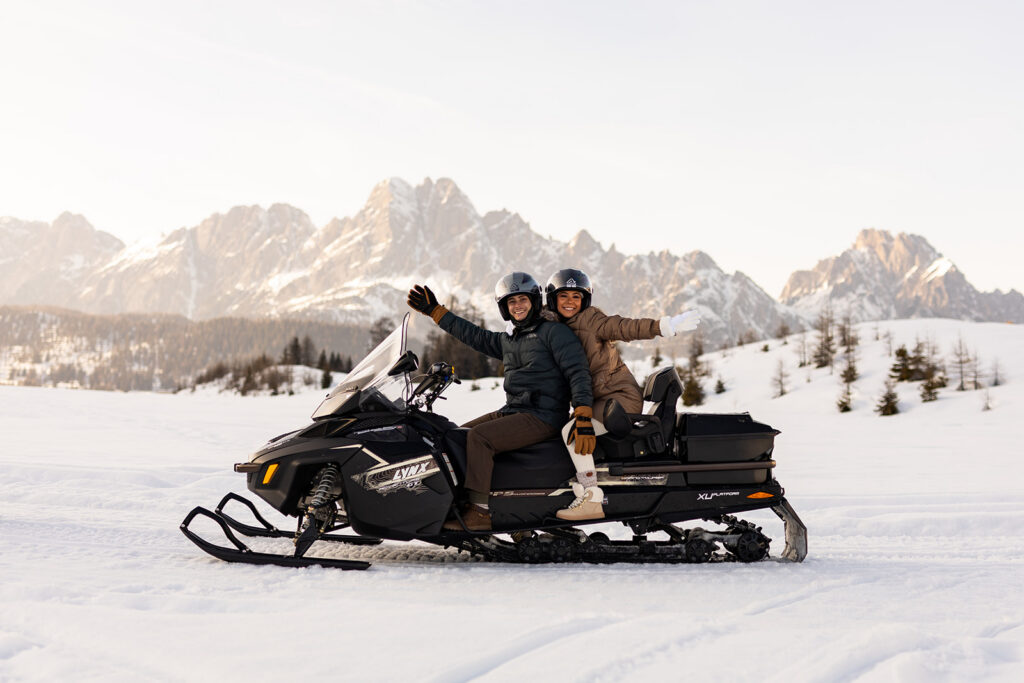 bride and groom having fun on the snowmobile during their snowmobile elopement in Dolomites