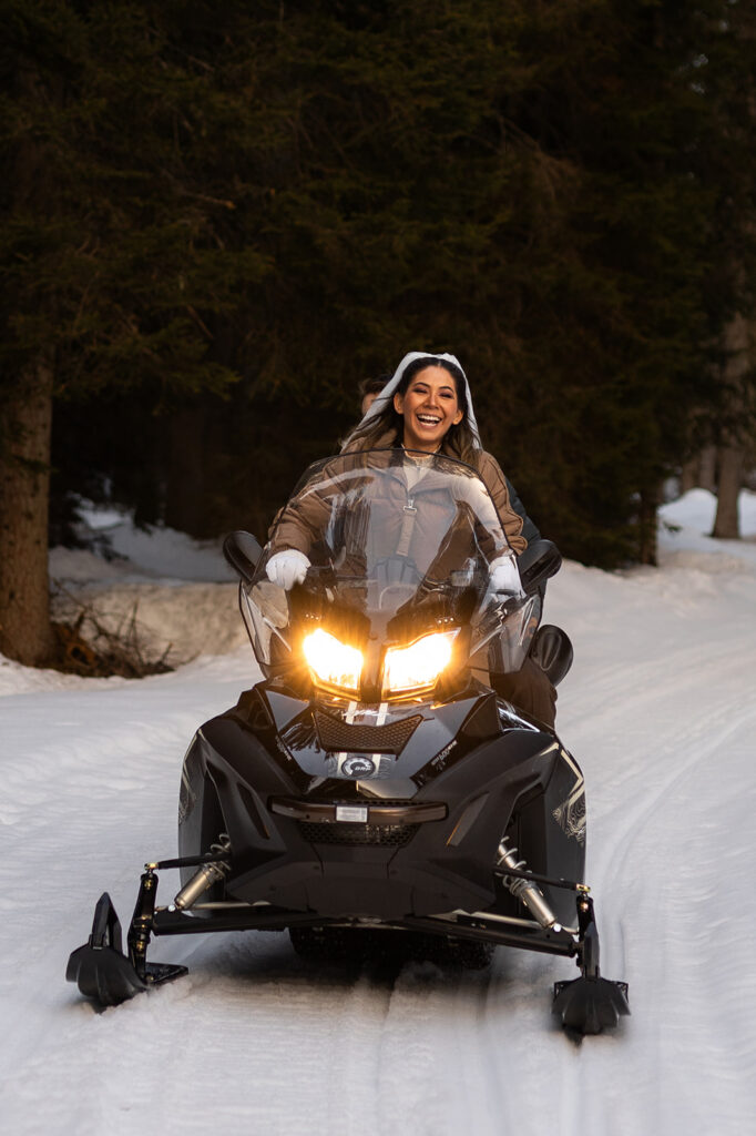 bride and groom riding a snowmobile during their adventure elopement in Dolomites