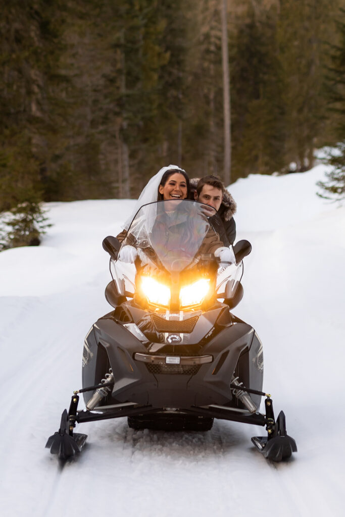 bride and groom having fun on the snowmobile during their snowmobile elopement in Dolomites