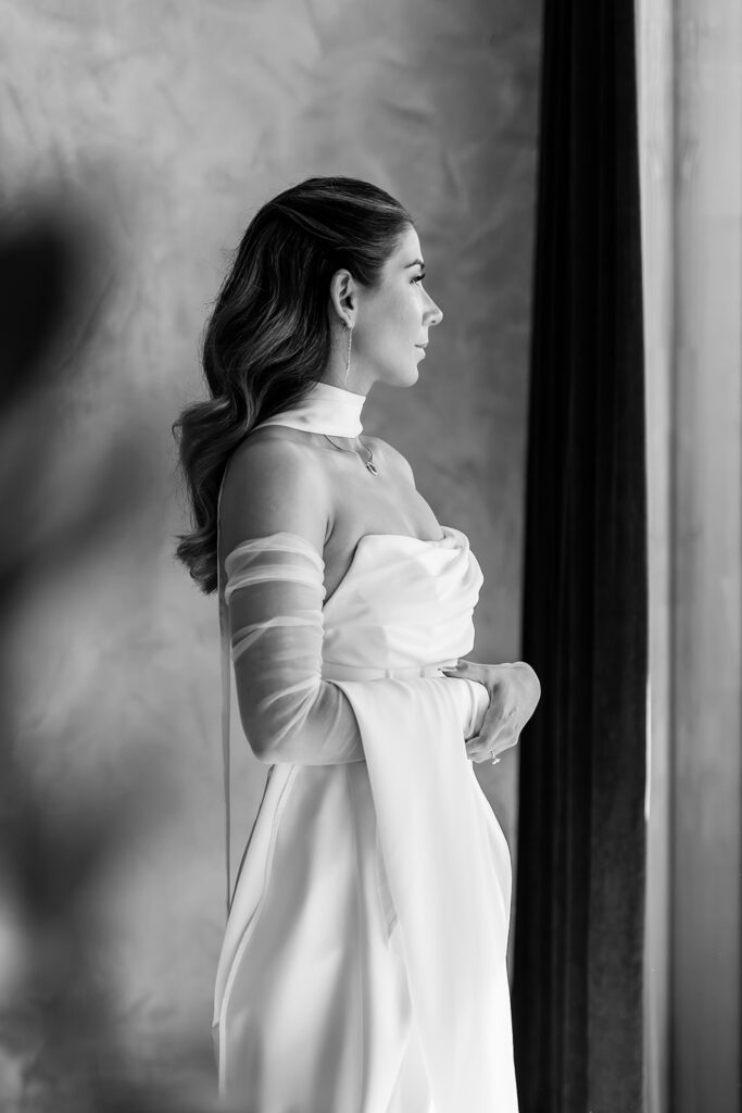 beautiful bride standing in front of the large window at the hotel with mountain views