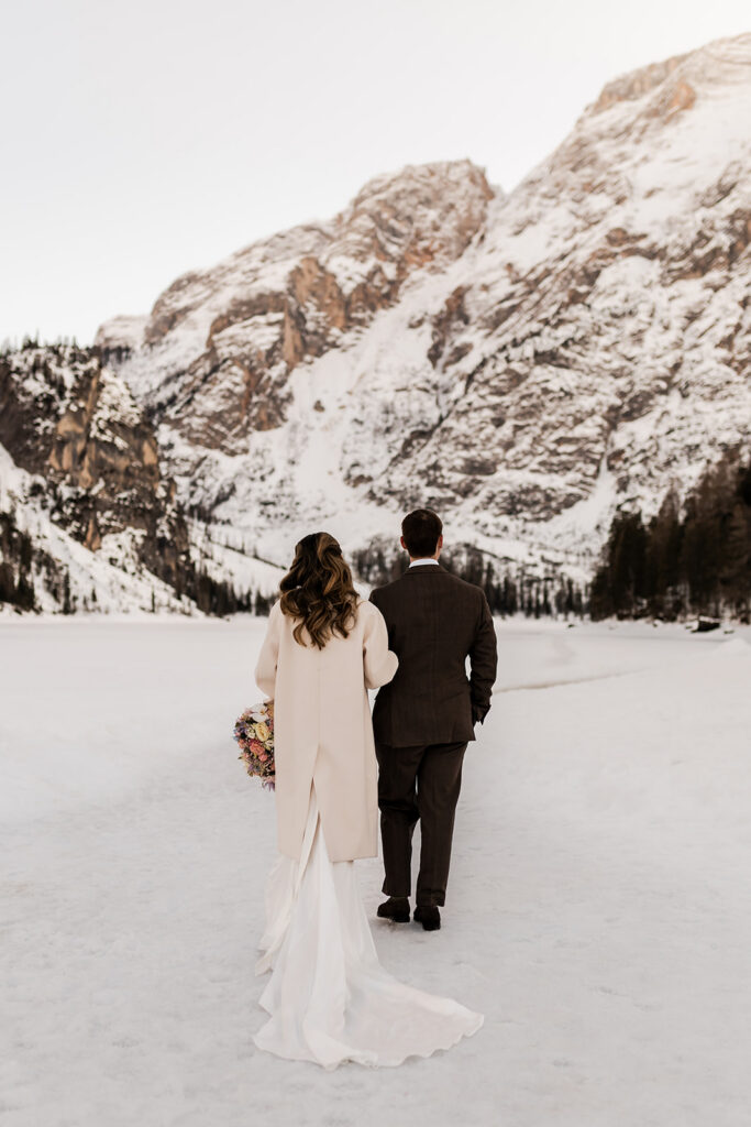 bride and groom exploring lake braies during their winter elopement in the dolomites