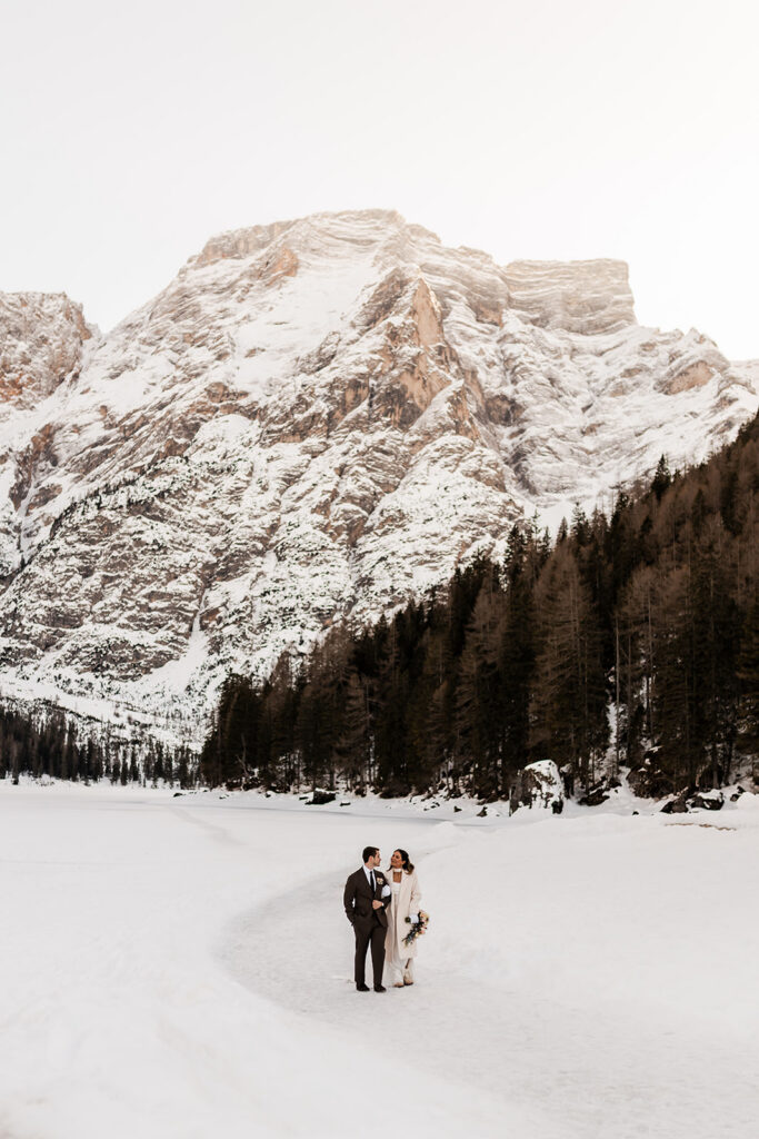 bride and groom exploring lake braies during their winter elopement in the dolomites