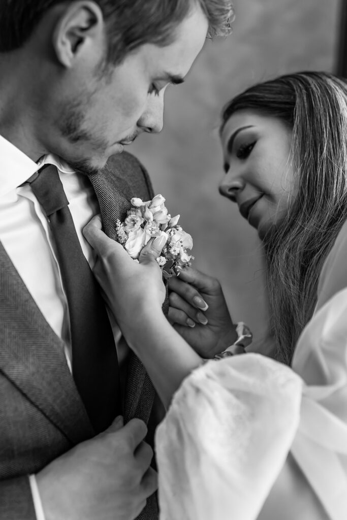 bride putting boutonniere ahead of their elopement in the Dolomites