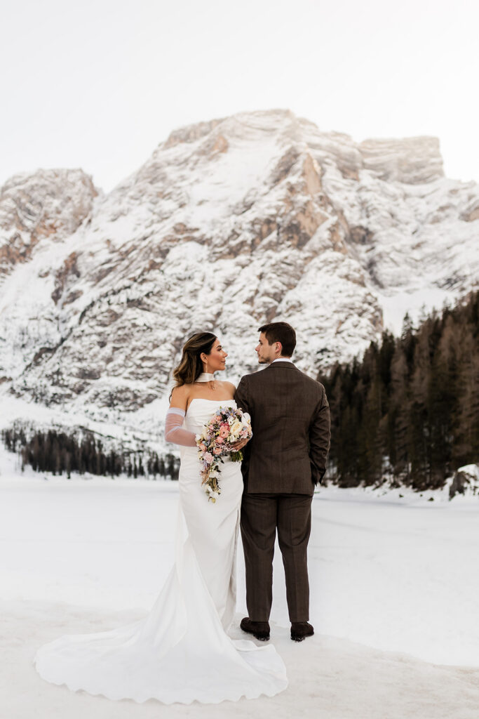 bride and groom standing in front of the snowy mountains in the Dolomites