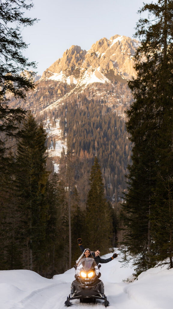 bride and groom riding a snowmobile during their adventure elopement in Dolomites