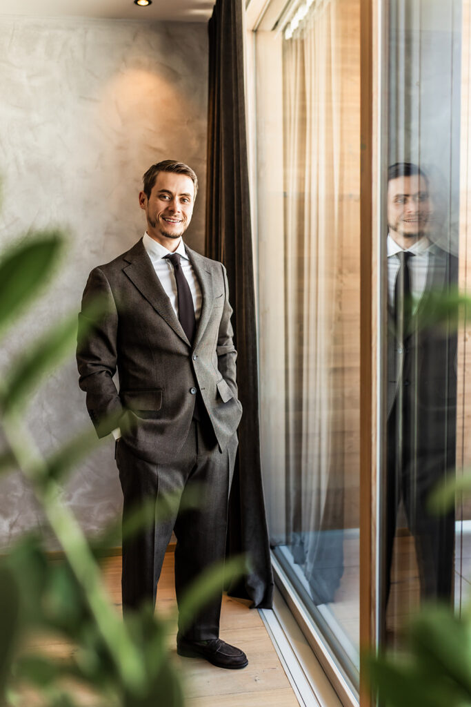 groom posing next to a large window