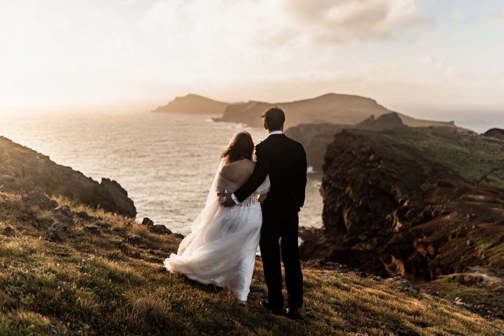 bride and groom holding each other while looking at the ocean during madeira elopement