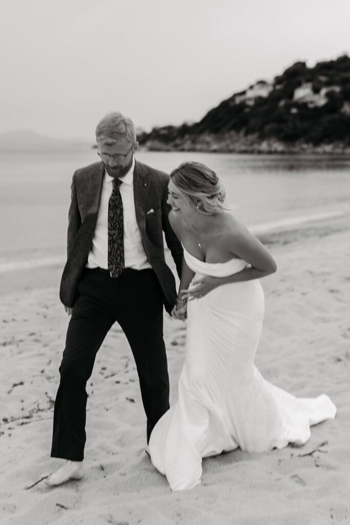 playful bride and groom at the beach in sardinia during blue hour
