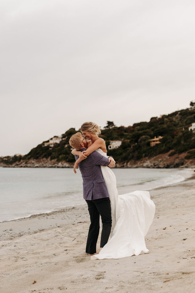 playful bride and groom at the beach in sardinia during blue hour