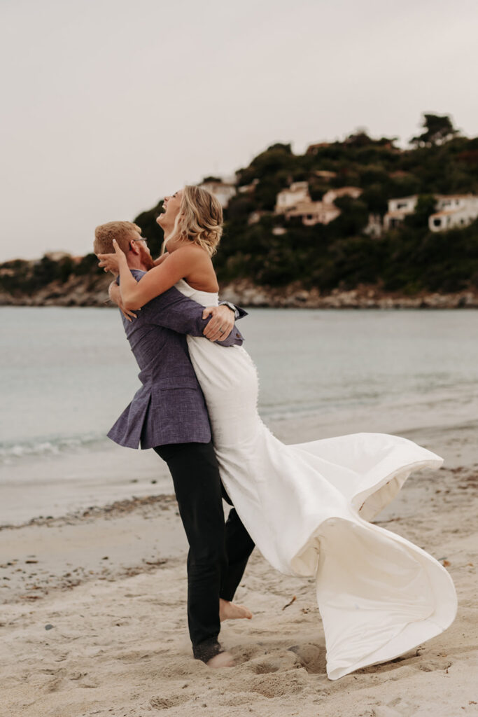 playful bride and groom at the beach in sardinia during blue hour