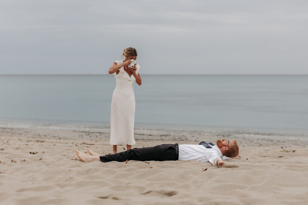 playful bride and groom at the beach in sardinia during blue hour