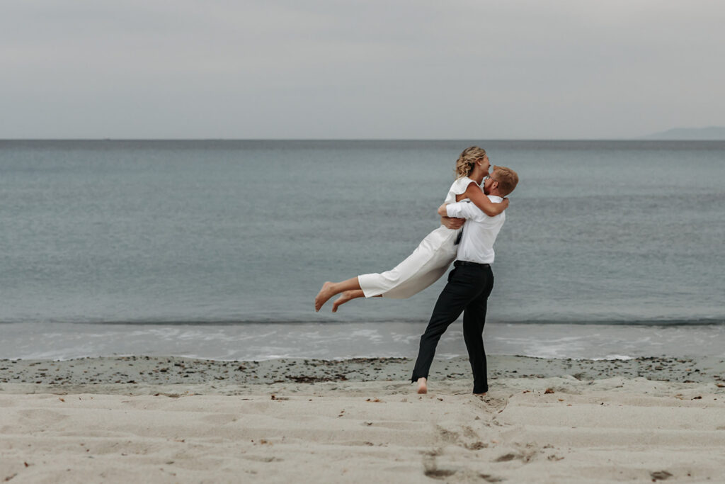 playful bride and groom at the beach in sardinia during blue hour
