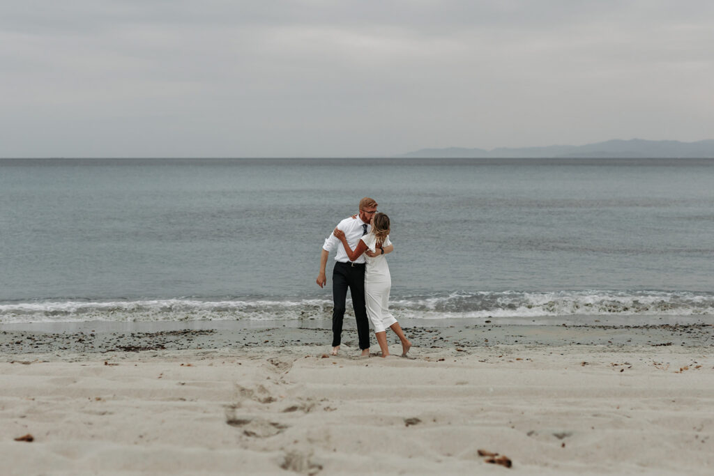 playful bride and groom at the beach in sardinia during blue hour