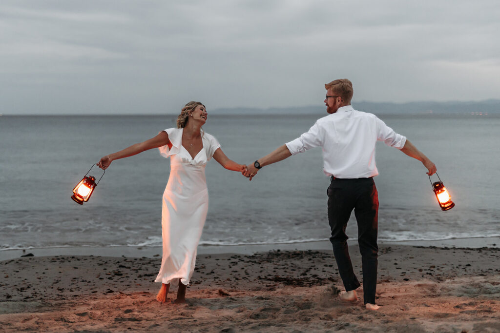 bride and groom with lanterns at the beach