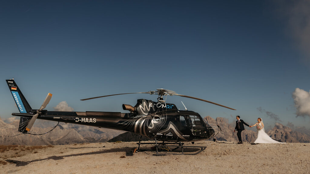 bride and groom standing next to the helicopter during their dolomites helicopter elopement