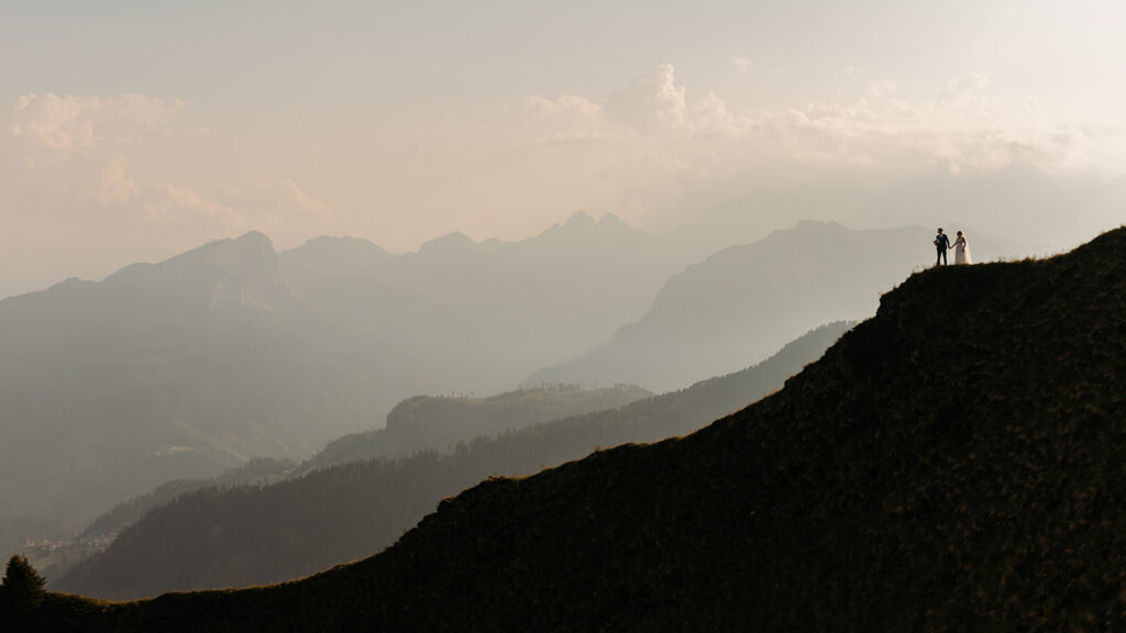 bride and groom standing on the edge of a mountain overlook in the dolomites